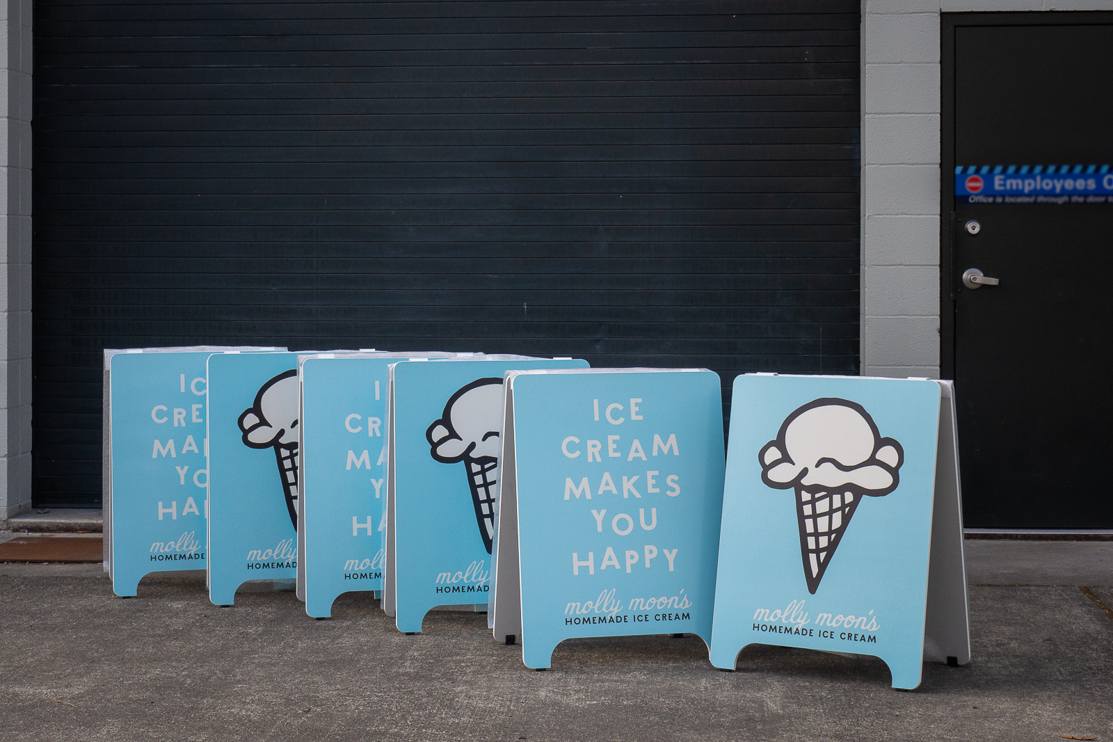 Two pale blue A-Frames that show either an ice cream cone or say "Ice Cream Makes You Happy" that Studio 3 Signs in Ballard produced for Molly Moon's.